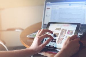 gambar seseorang sedang memakai tablet untuk cek sesuatu. Gambar ini dipakai untuk featured image artikel membahas website bisnis di Portofolio Jeremi Napoli Siregar.